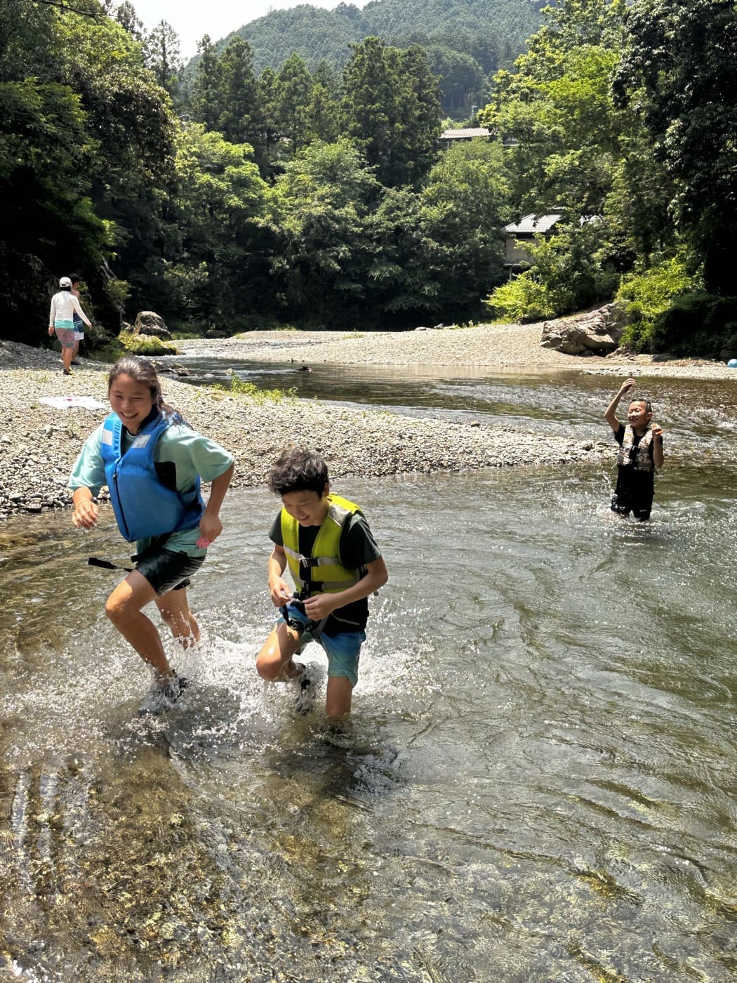 澄んだ川を歩いて遊ぶ子どもたち