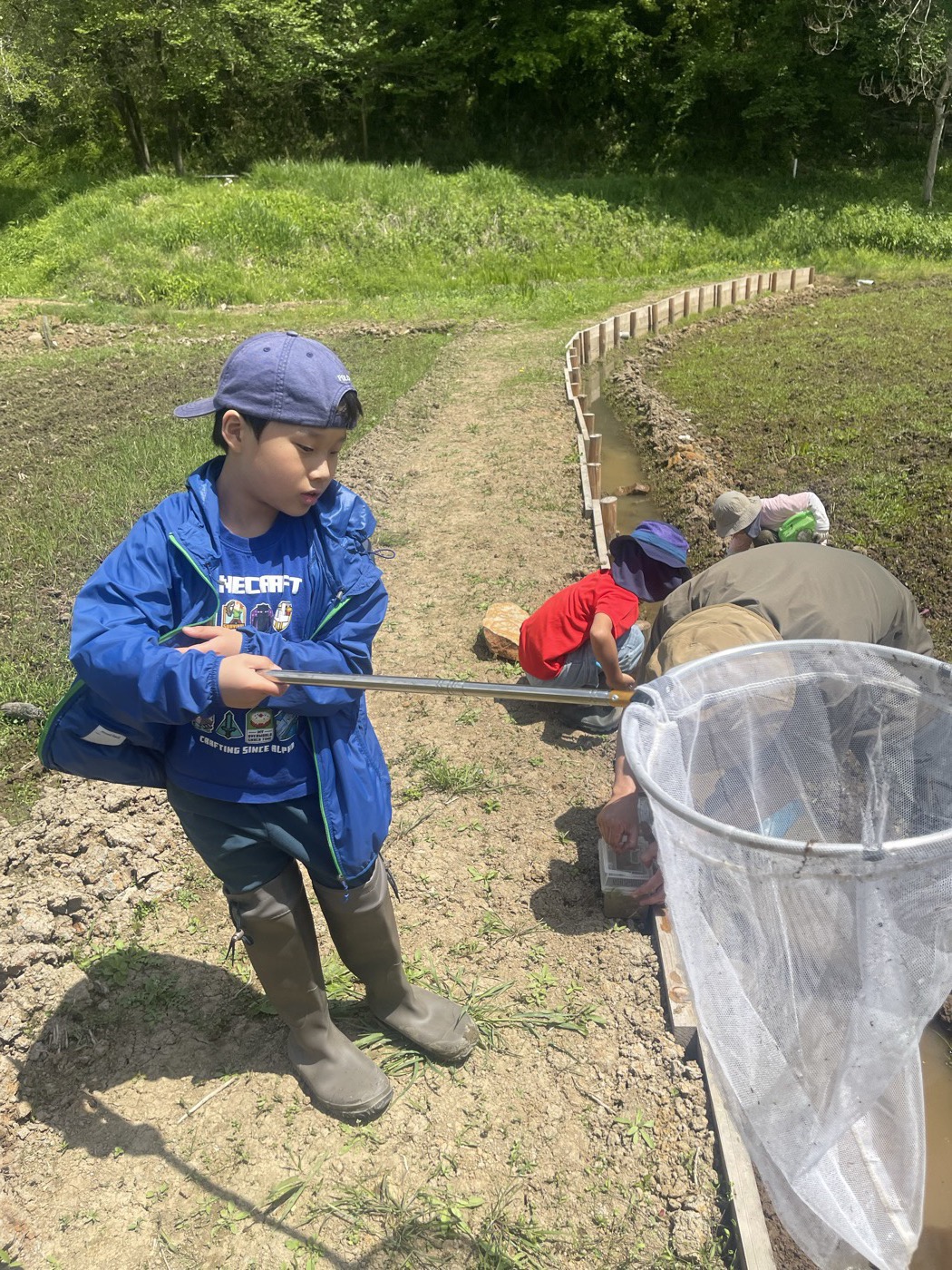 陸で網を使っていきものを探す子ども