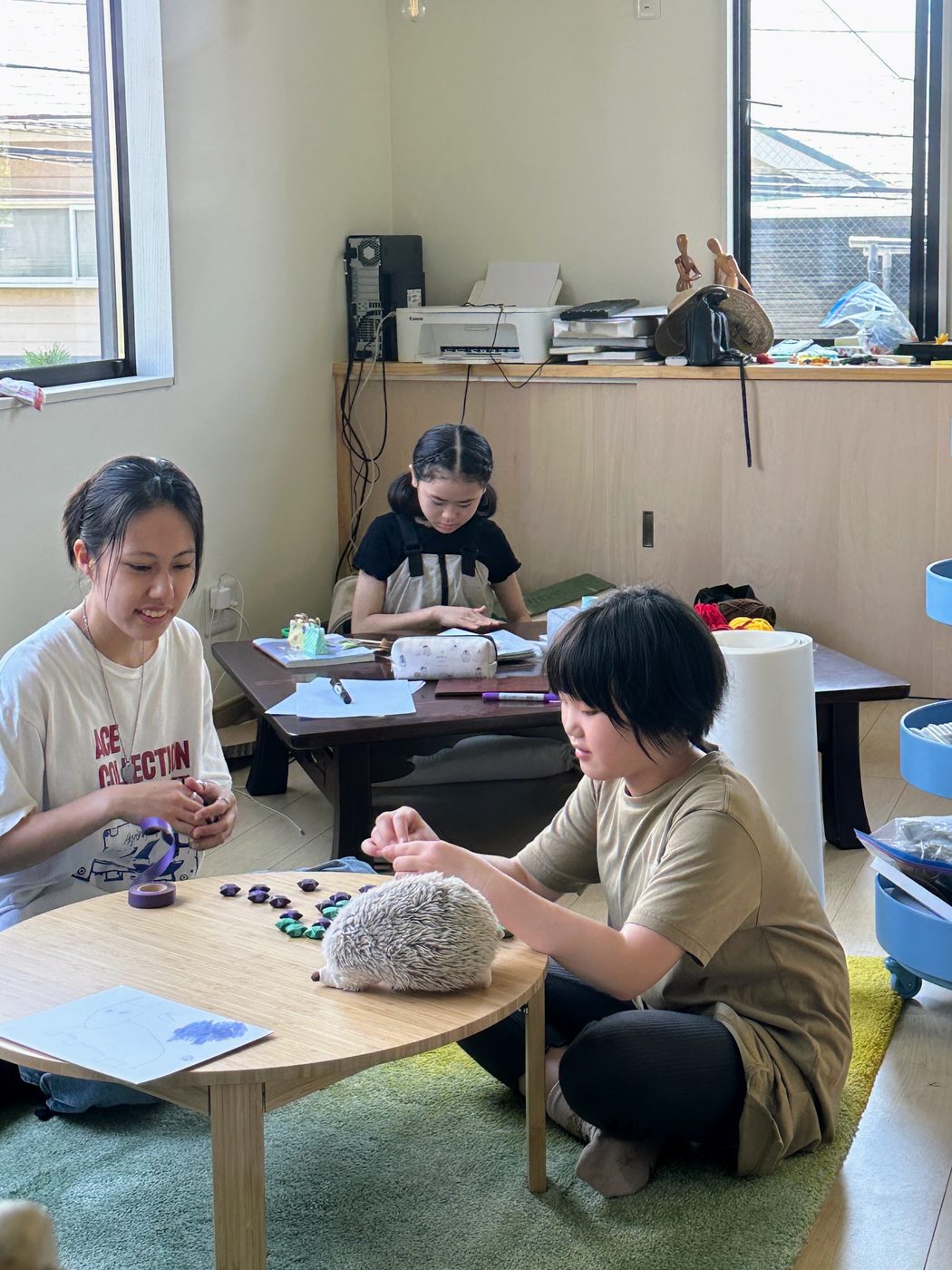 海辺のアトリエの作業机に向かって手を動かす子どもたち